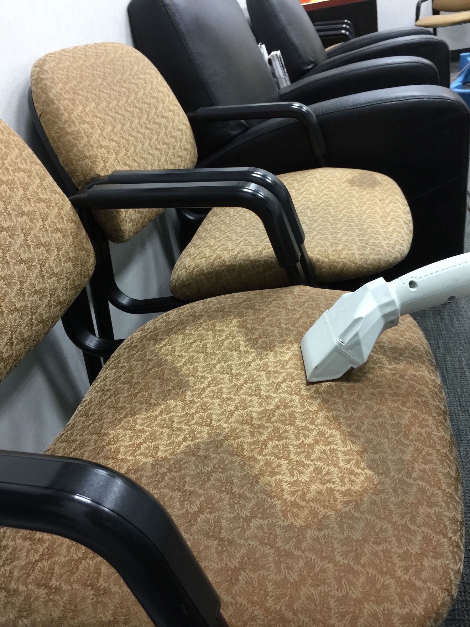 A vacuum cleaner is cleaning a chair in a waiting room.