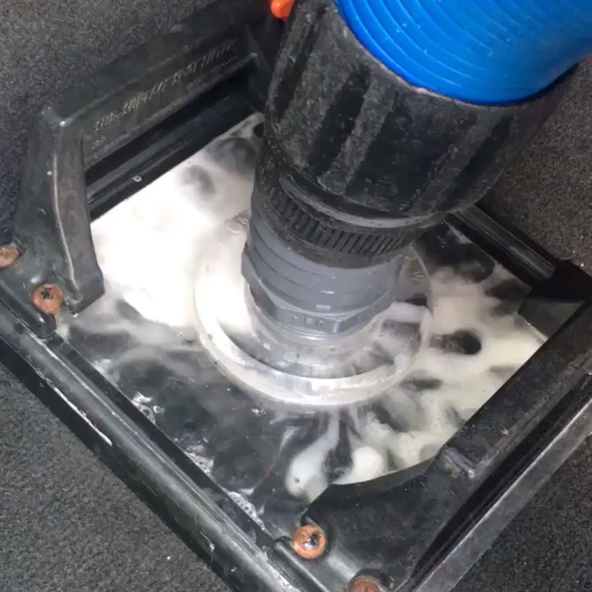 A vacuum cleaner is being used to clean a drain