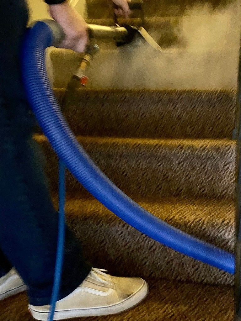A person is cleaning stairs with a vacuum cleaner.