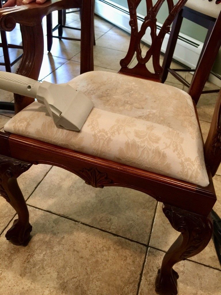 A chair is being cleaned with a vacuum cleaner.