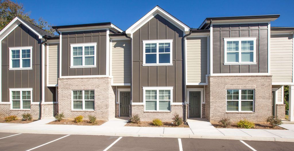 A row of apartment buildings with a parking lot in front of them.