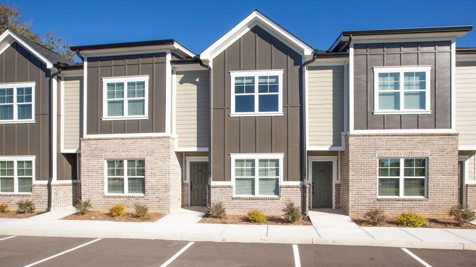 A row of apartment buildings with a parking lot in front of them.