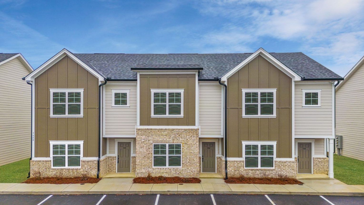 A row of apartment buildings with a parking lot in front of them.