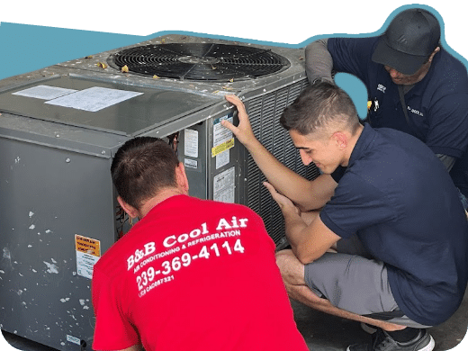 Three technicians working on an AC unit. One in red shirt with logo, two in dark shirts. Outdoors.