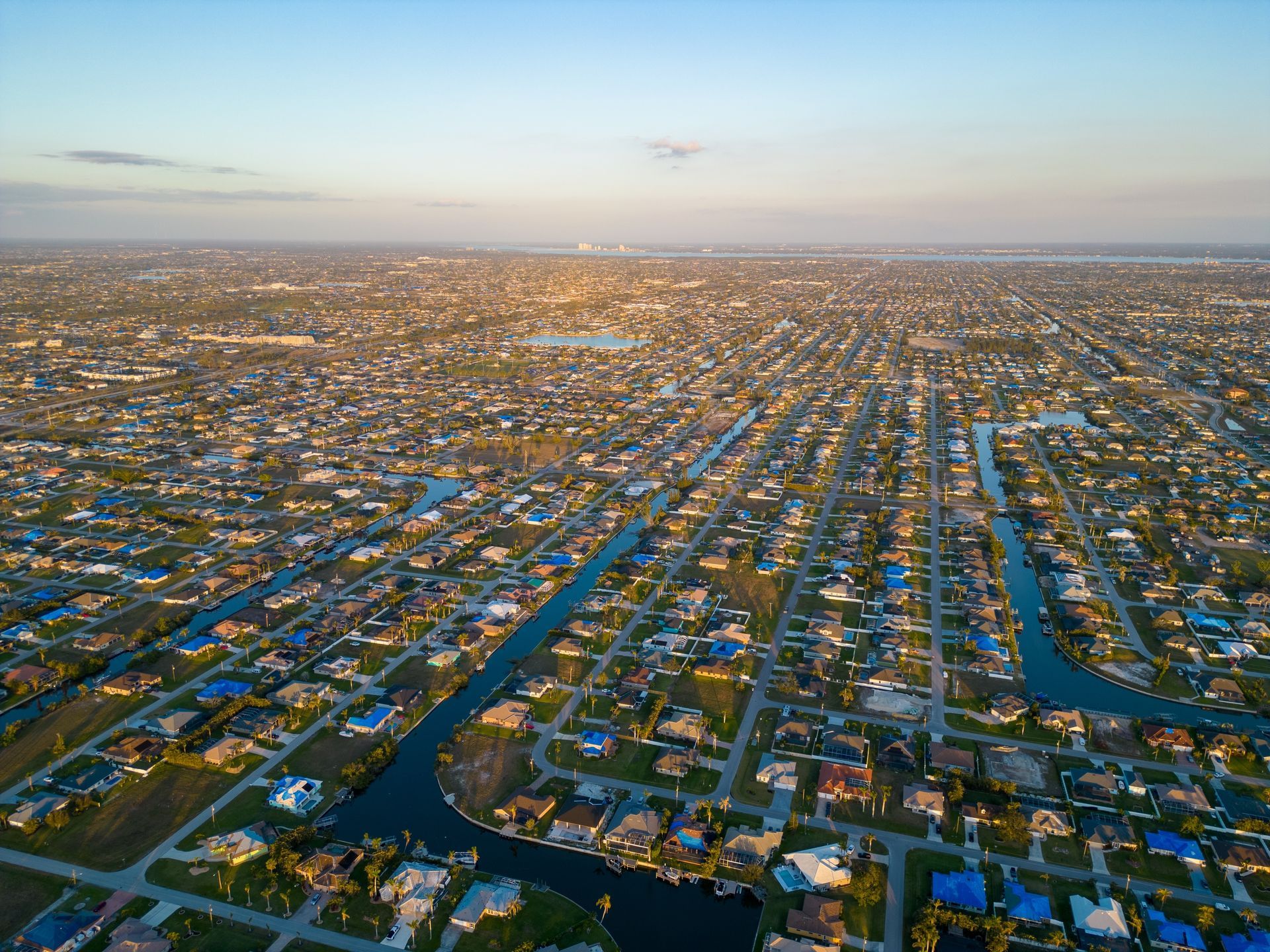Aerial view of a suburban neighborhood with many houses, canals, and roads.