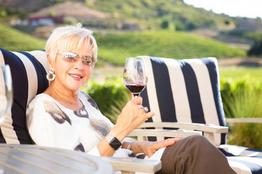 A woman is sitting in a chair holding a glass of wine.