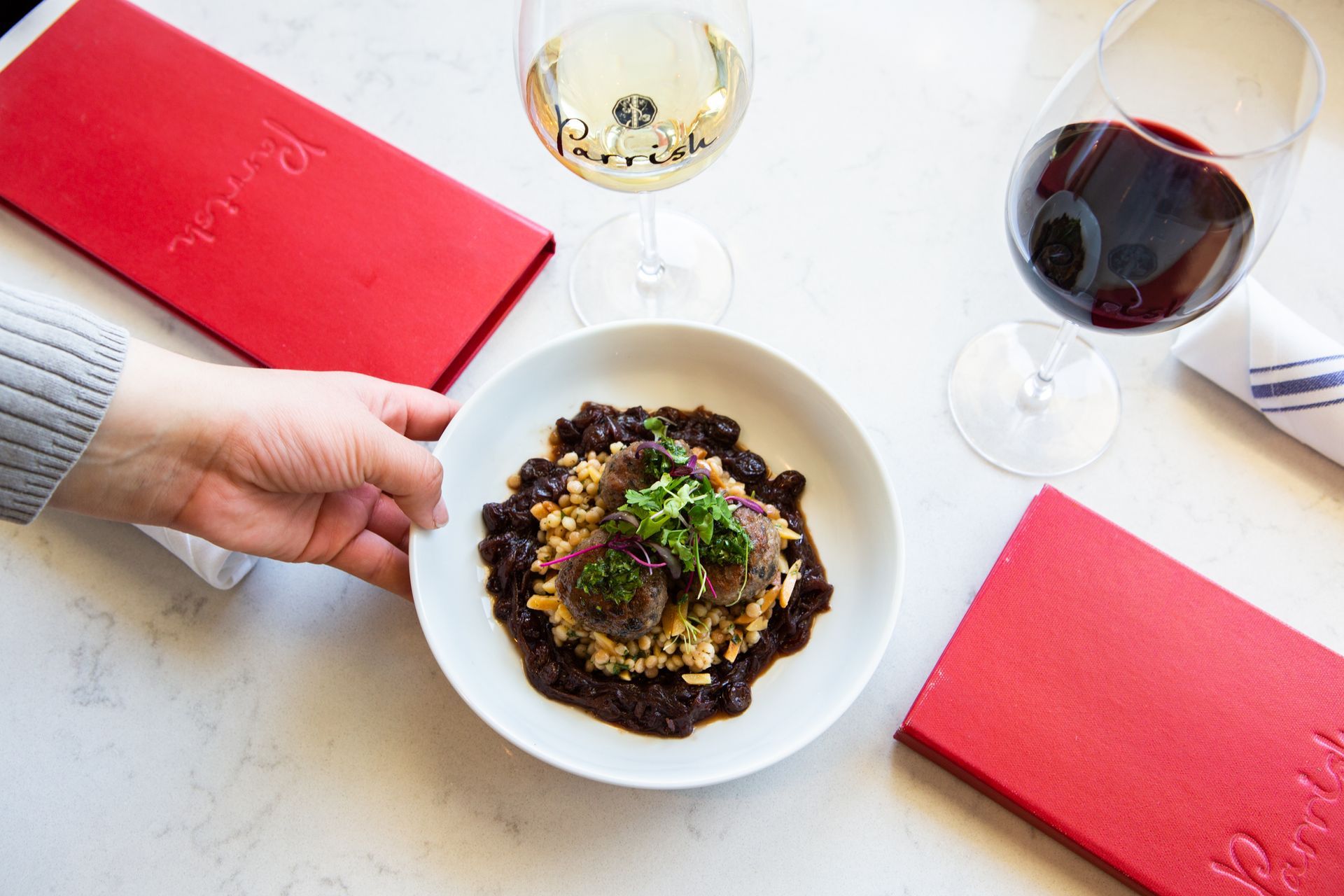 A bottle of parrish red wine next to a plate of food.
