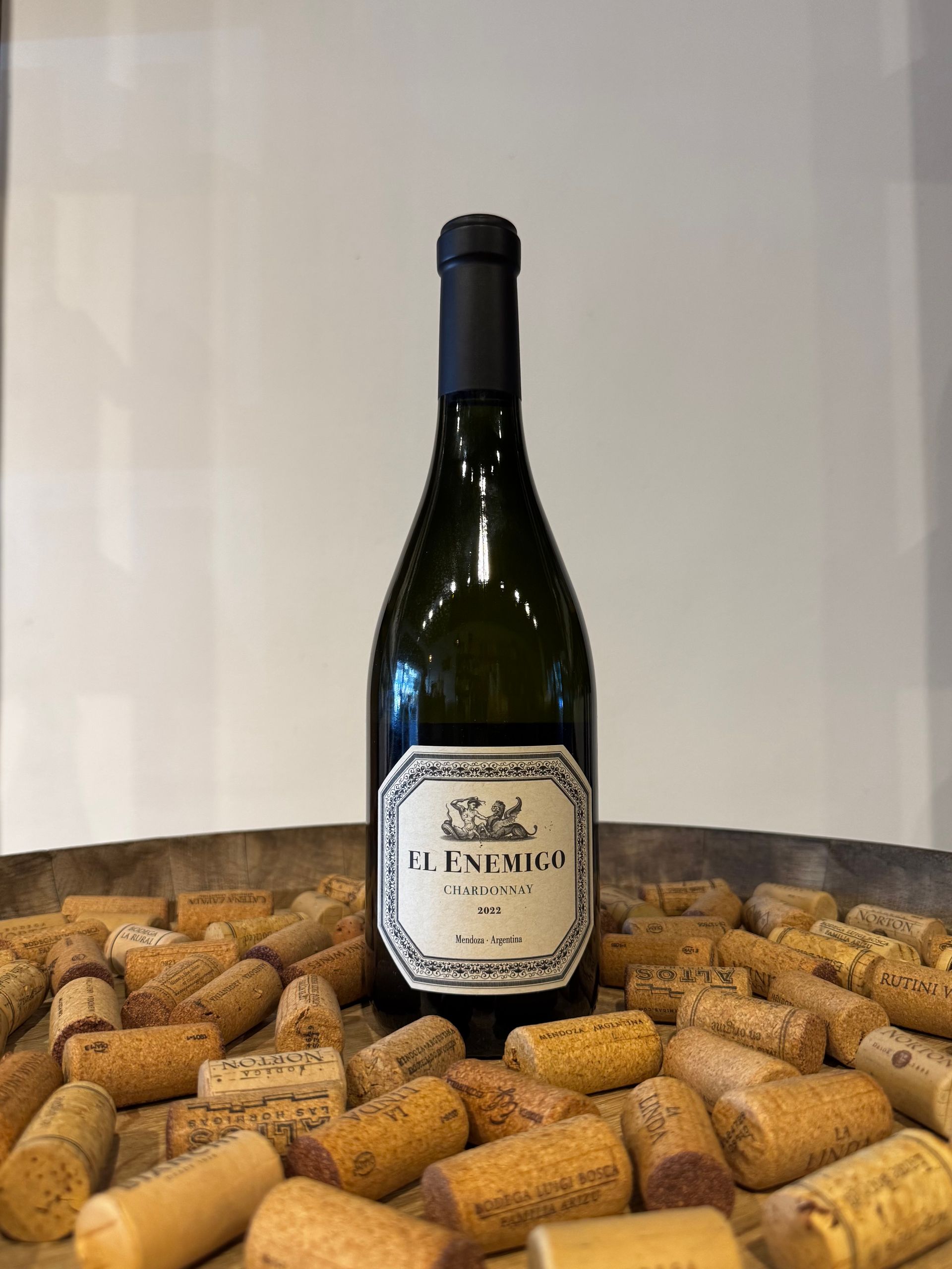 Botella de vino, centrada, sobre un lecho de corchos; etiqueta visible.