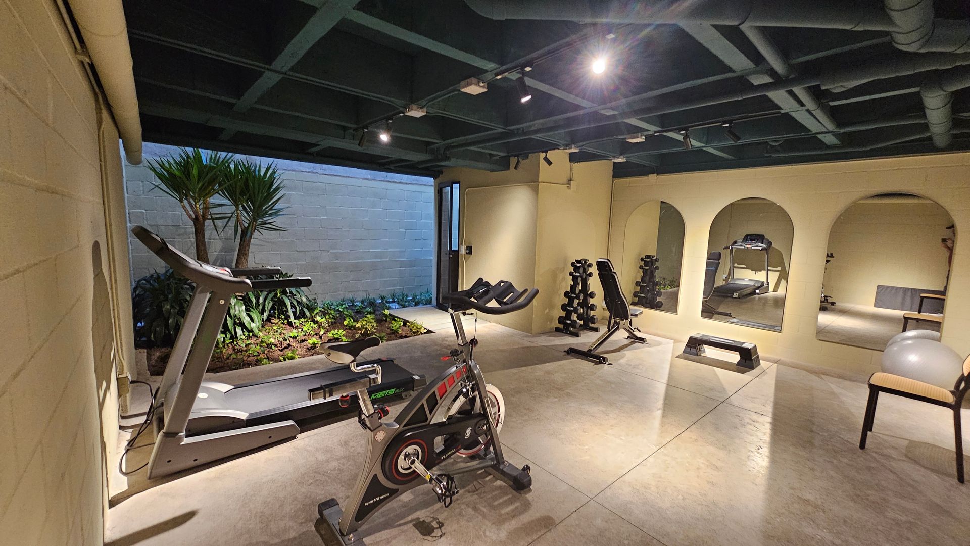 A gym with a treadmill , exercise bike , and dumbbells.