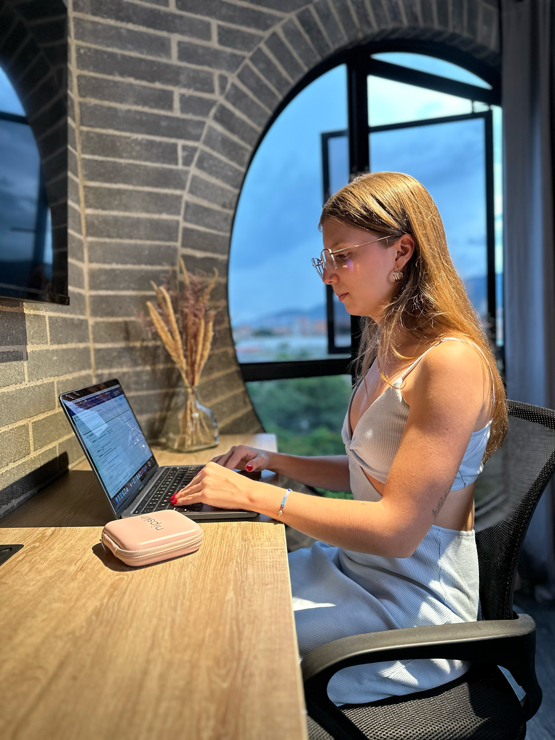 A woman is sitting at a desk using a laptop computer.