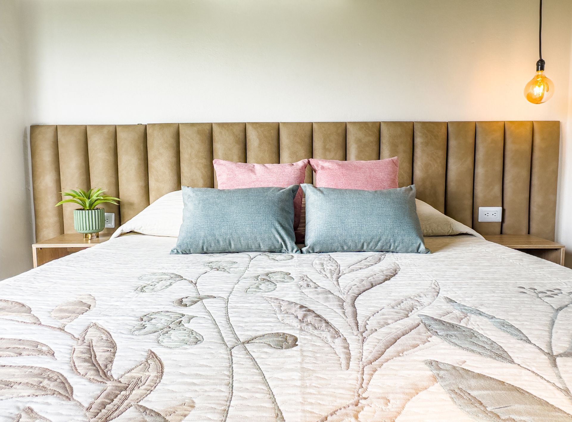 A bed with a floral blanket and pillows in a bedroom.