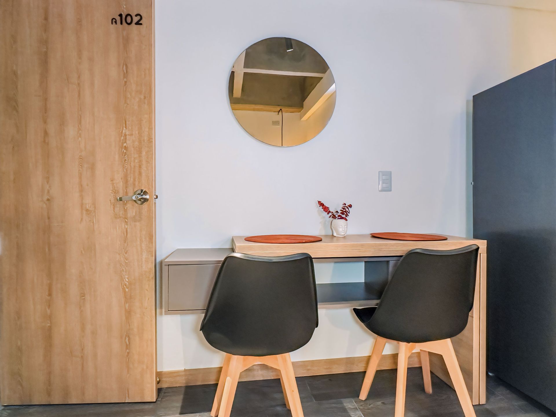 A room with a desk and chairs and a mirror on the wall.