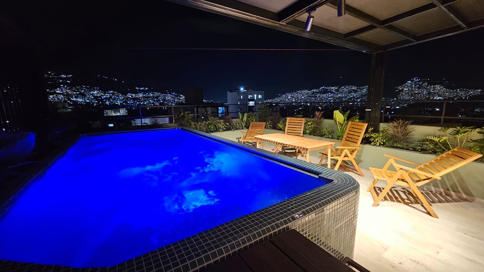 A laptop sits on a wooden desk next to a potted plant
