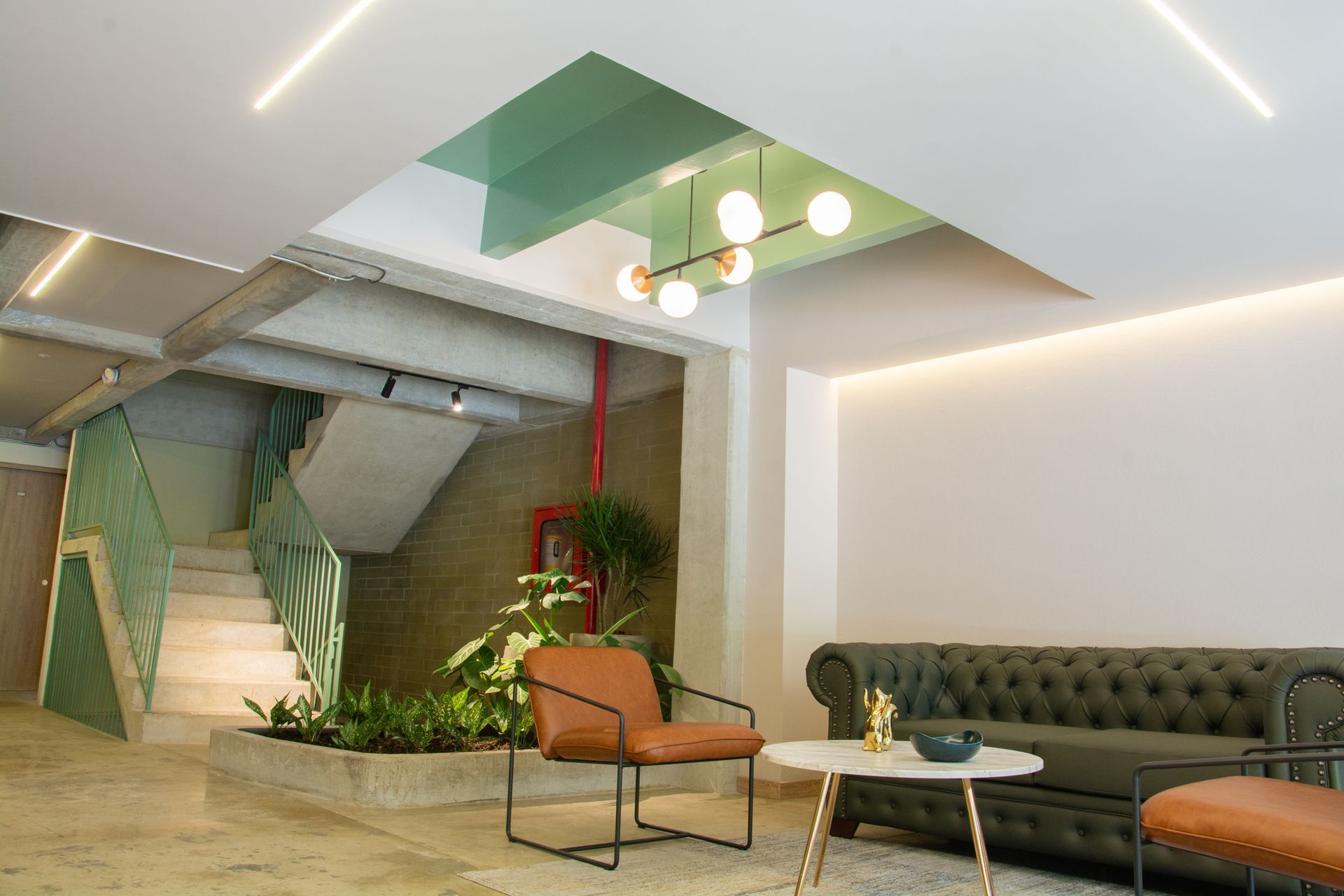 A living room with a couch , chair , table and stairs.