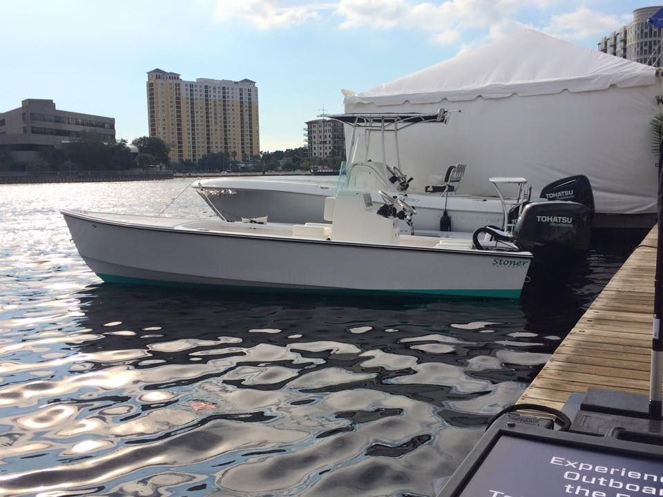 A row of boats are covered in white tarps and sitting on trailers.