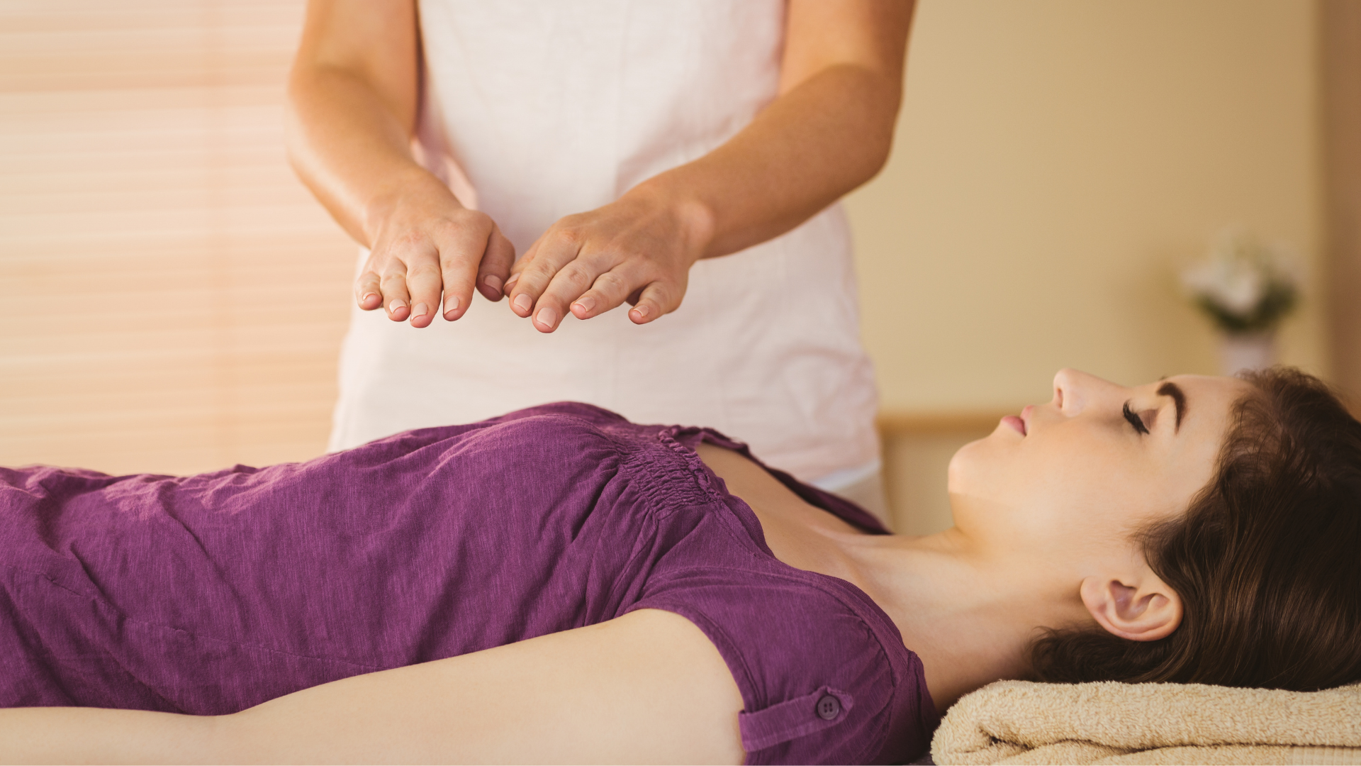 Una mujer está acostada en una cama recibiendo un tratamiento de reiki.