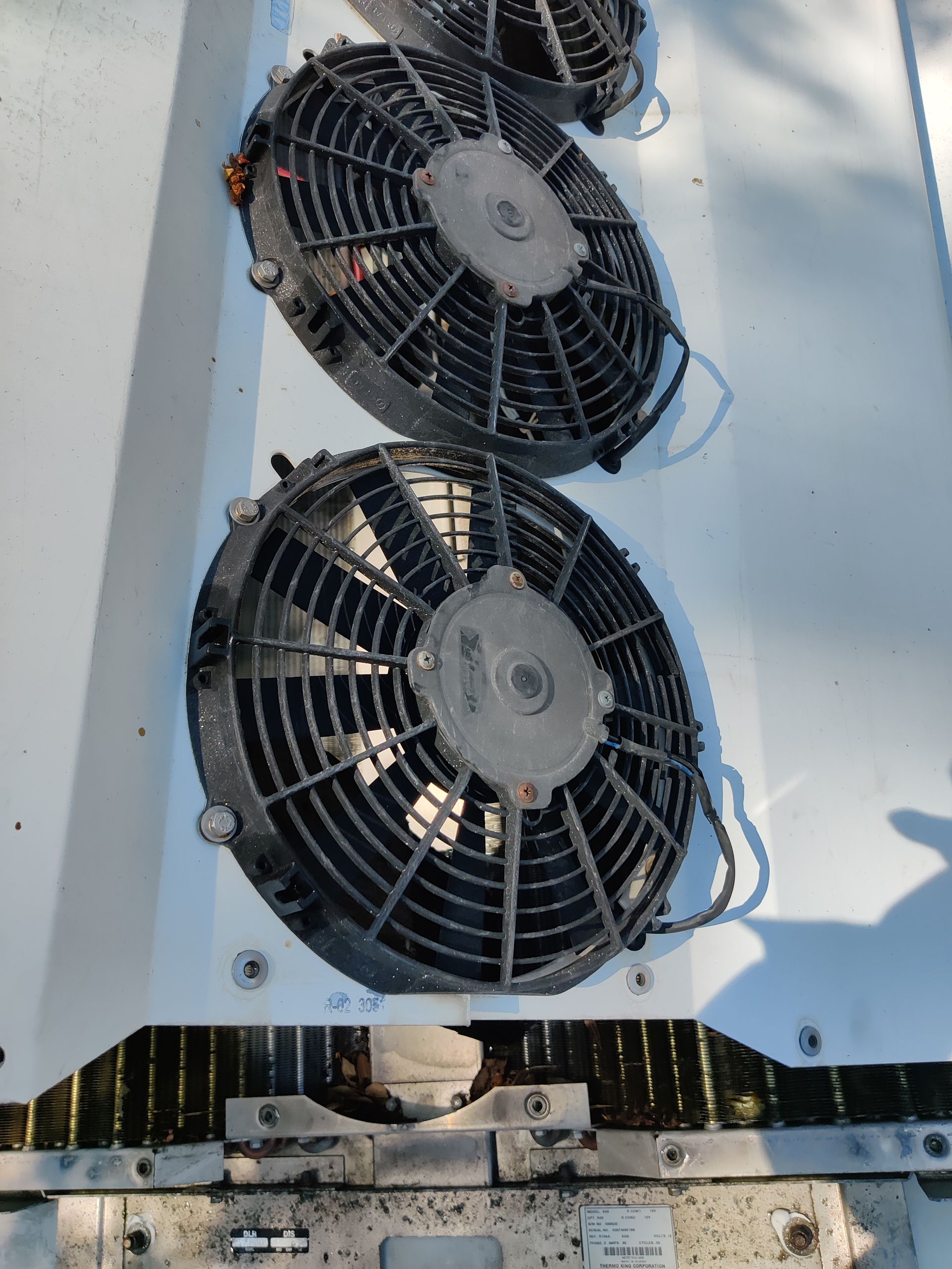 Three black radiator fans attached to a white surface.