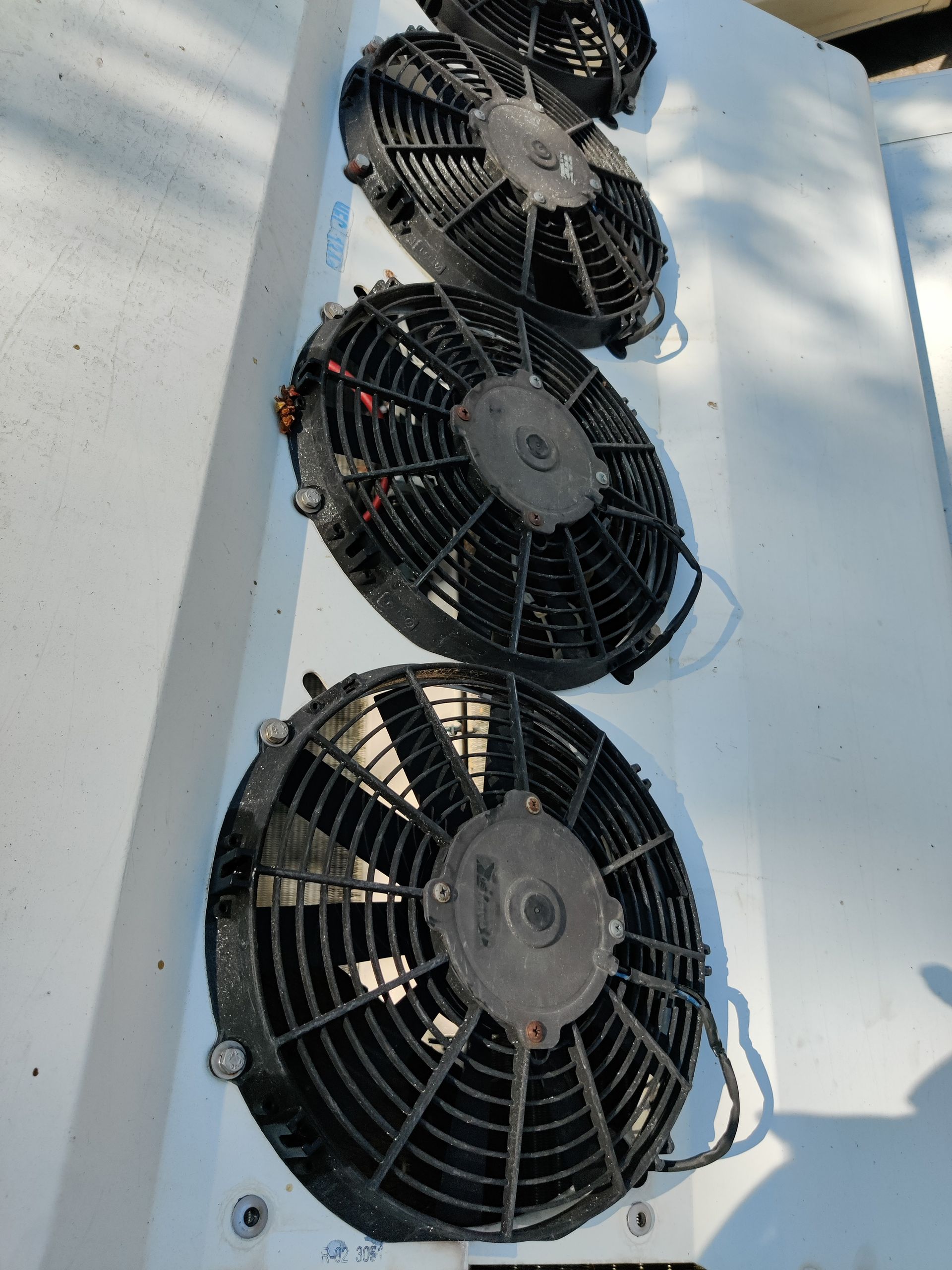 Four black electric fans mounted on a white surface, likely for cooling.
