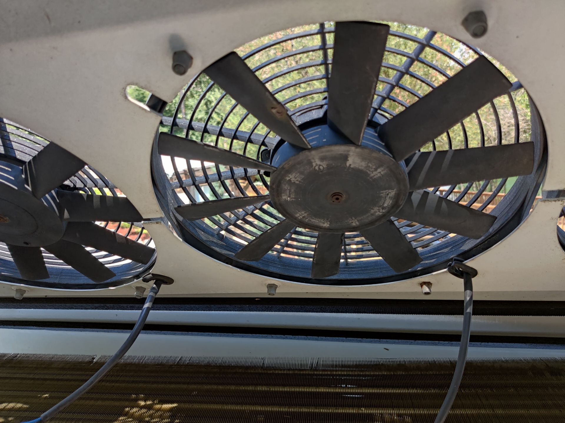 Three large industrial fans with black blades mounted on a white surface, blowing air.