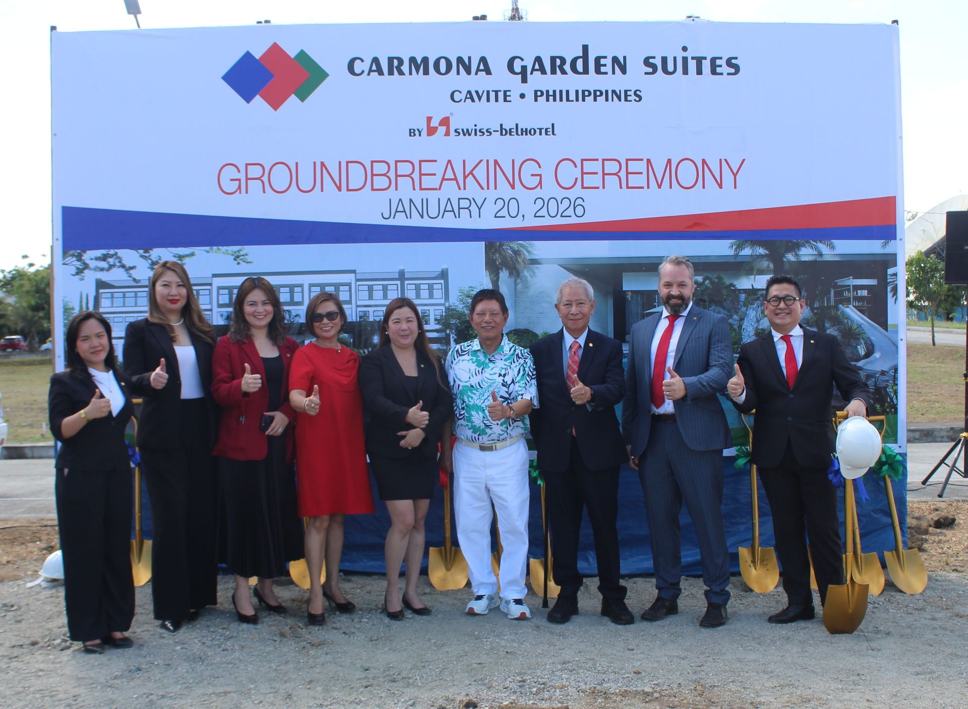 Group at Carmona Garden Suites groundbreaking ceremony in Cavite, Philippines. Attendees giving thumbs up near a banner.