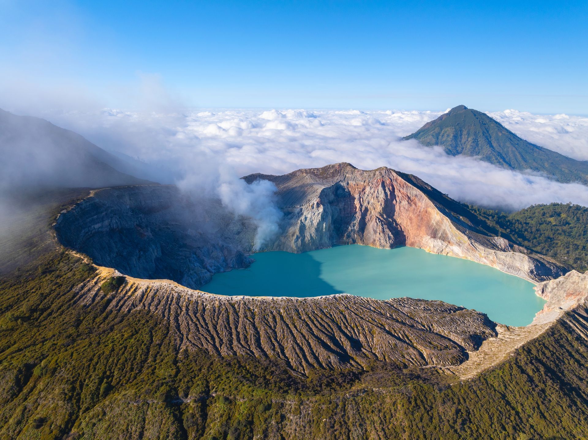 Aerial view of Kawah Ijen volcano in Indonesia, turquoise lake in crater, steam, mountains.