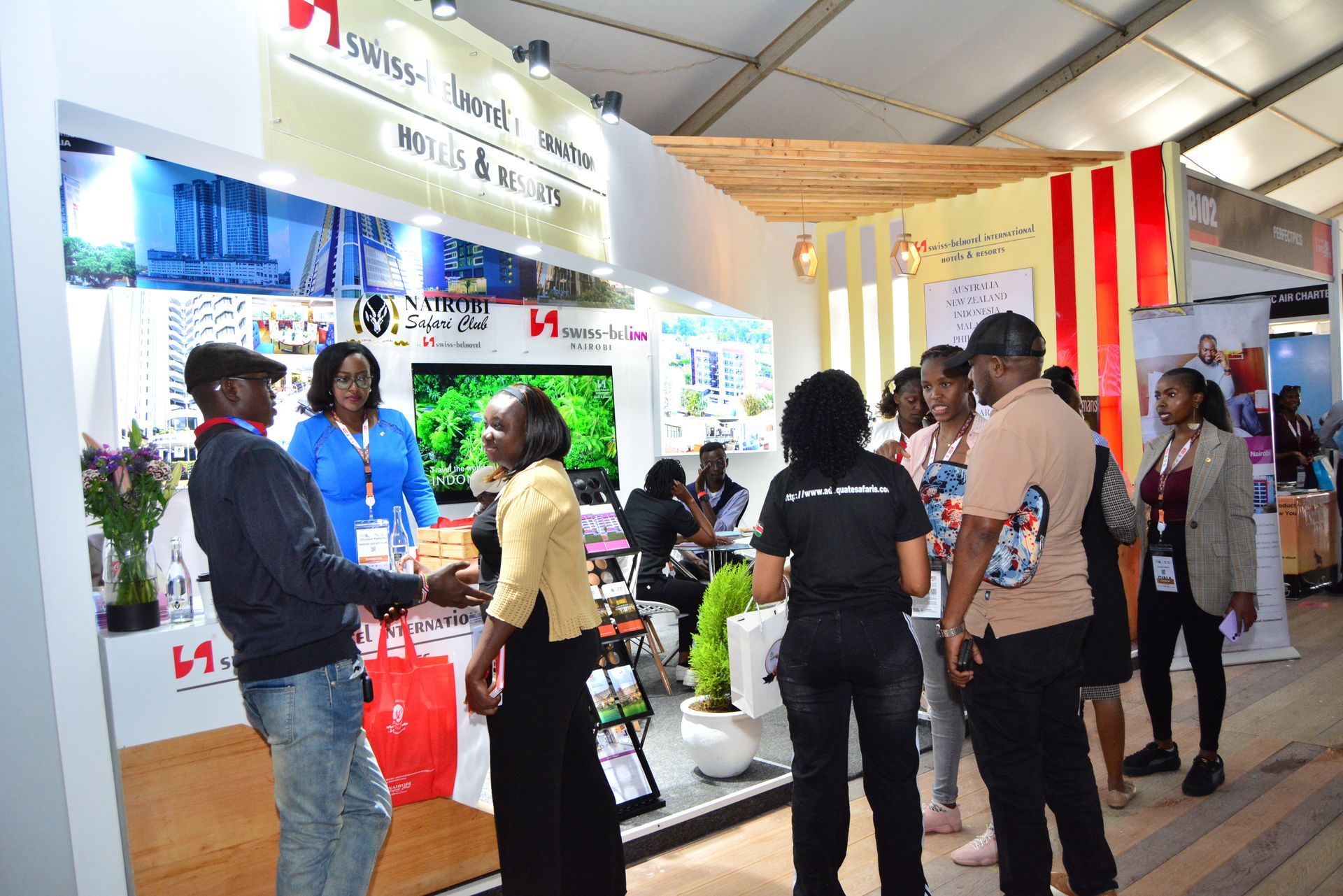 People at a trade show booth with a Swiss-themed banner. Various people interact, some looking at displayed items.
