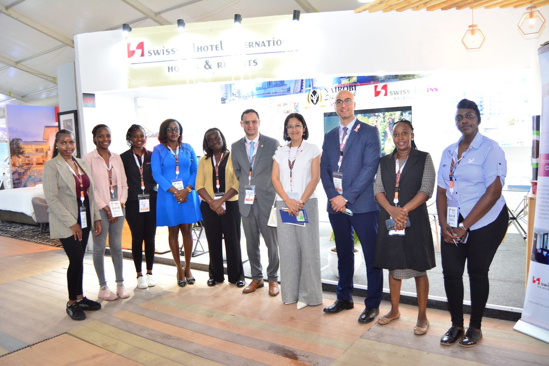 Group of people posing for a photo at a booth in a convention.