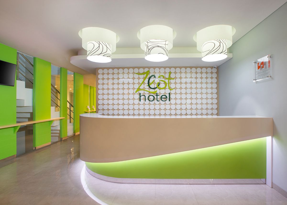 Hotel lobby with a curved reception desk, lit with green and white accents. 