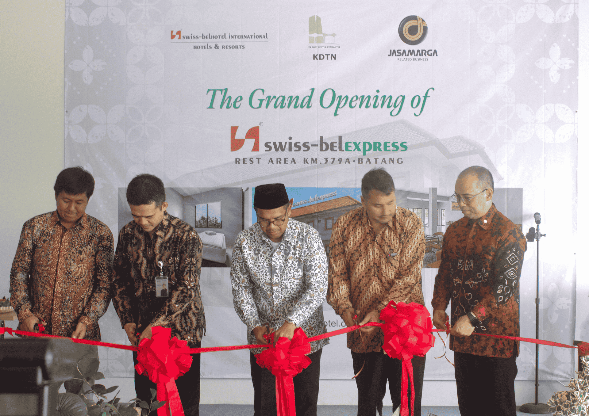 Five men cut a red ribbon at the 