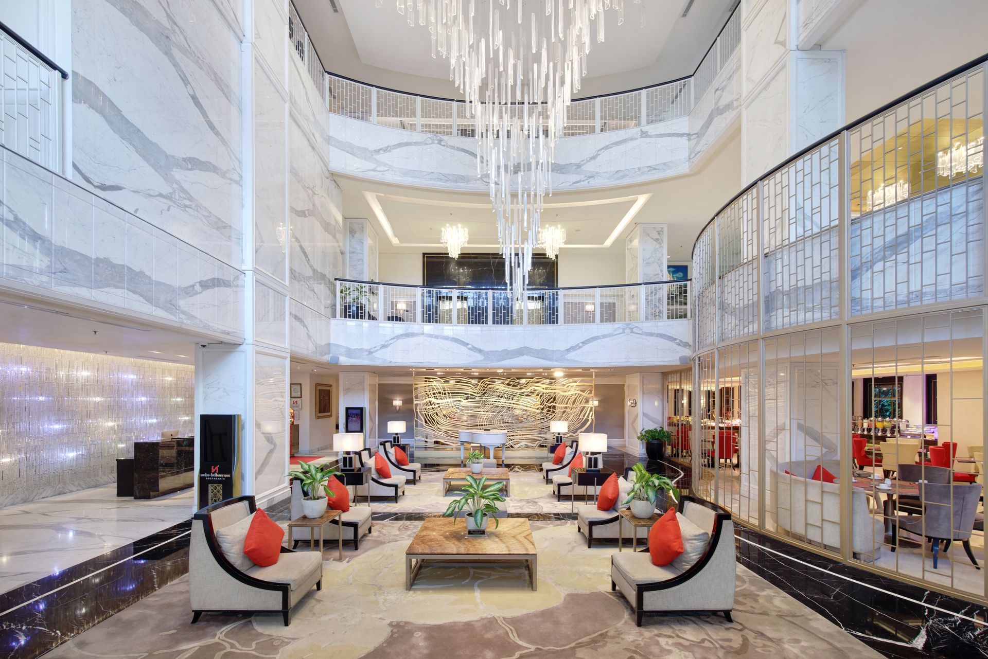 Luxurious hotel lobby with marble walls, seating areas, and a chandelier.