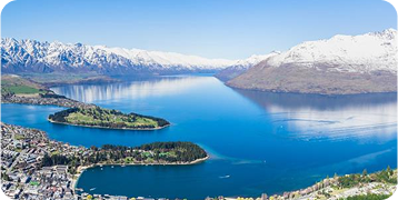 There are two islands in the middle of a lake surrounded by snow covered mountains.