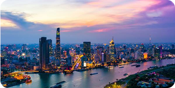 An aerial view of a city at night with a river in the foreground.