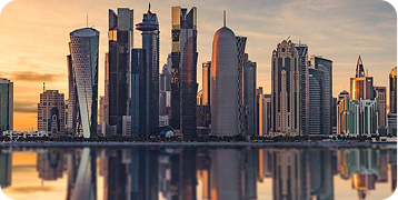 A city skyline is reflected in the water at sunset.