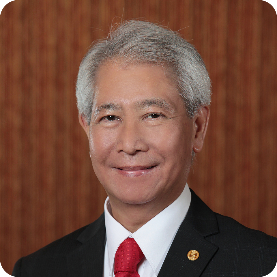 Smiling man in a suit with a red tie, against a brown backdrop.