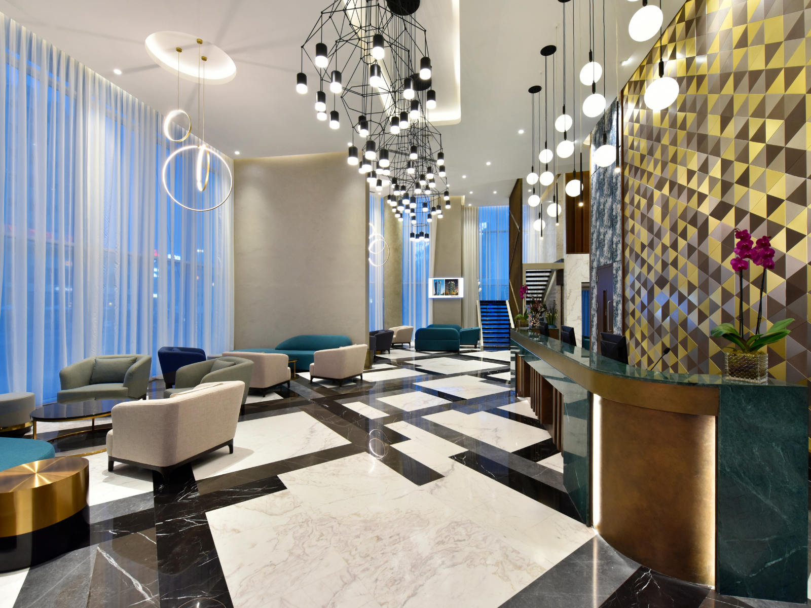 Hotel lobby with seating area, patterned floor, reception desk, and decorative lighting.