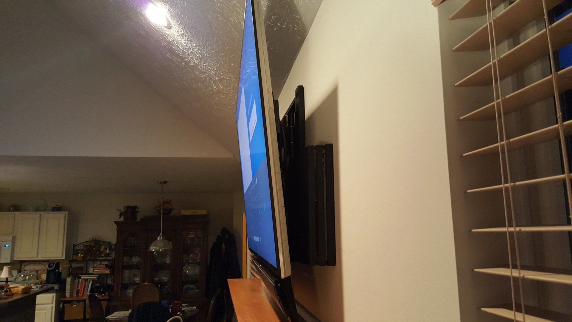 a flat screen tv is mounted on a wall in a living room with a game system mounted behind the TV in northern ohio