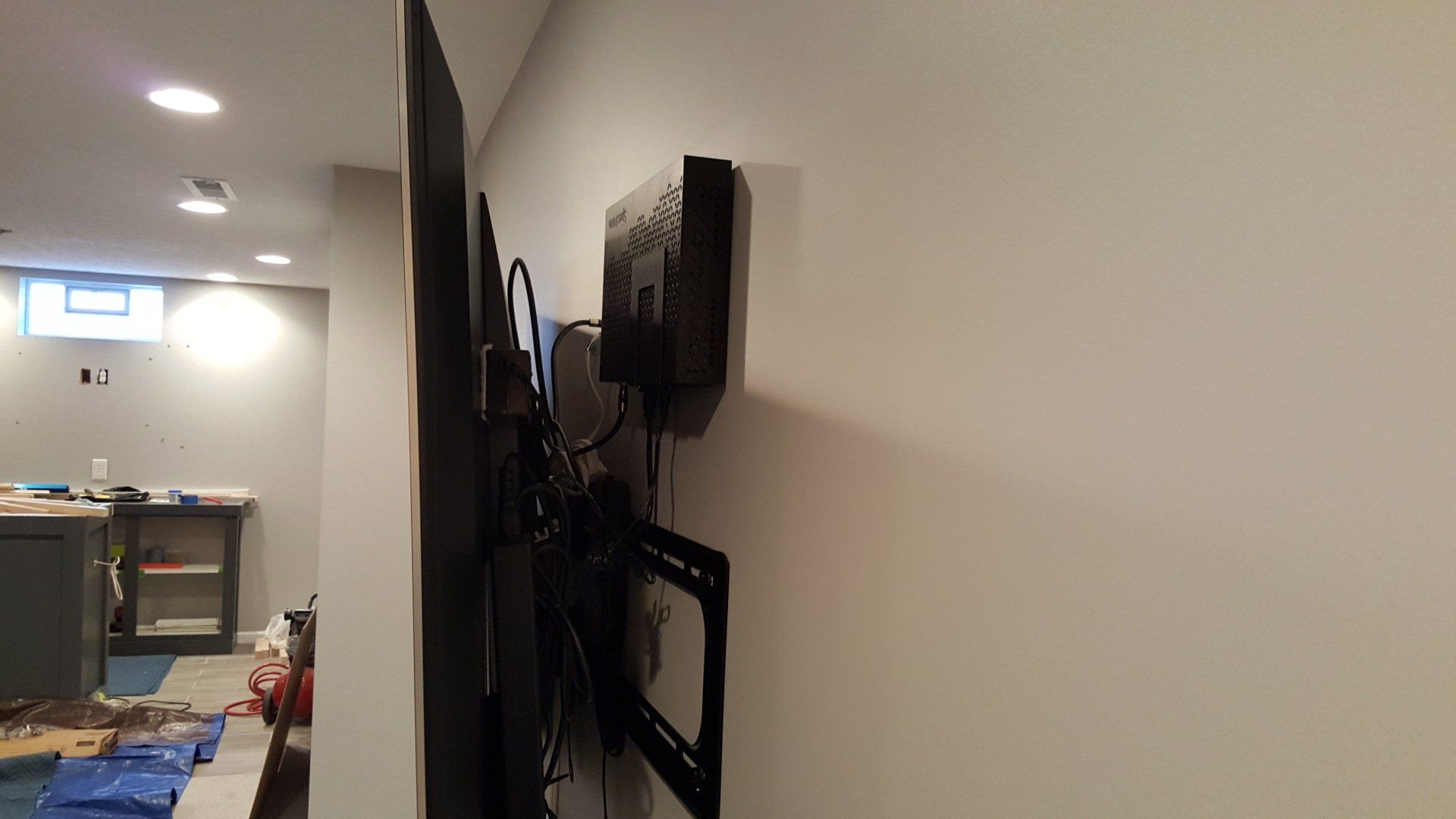 a tv mounted on a wall with a streaming box and cable box mounted behind the TV in northern ohio