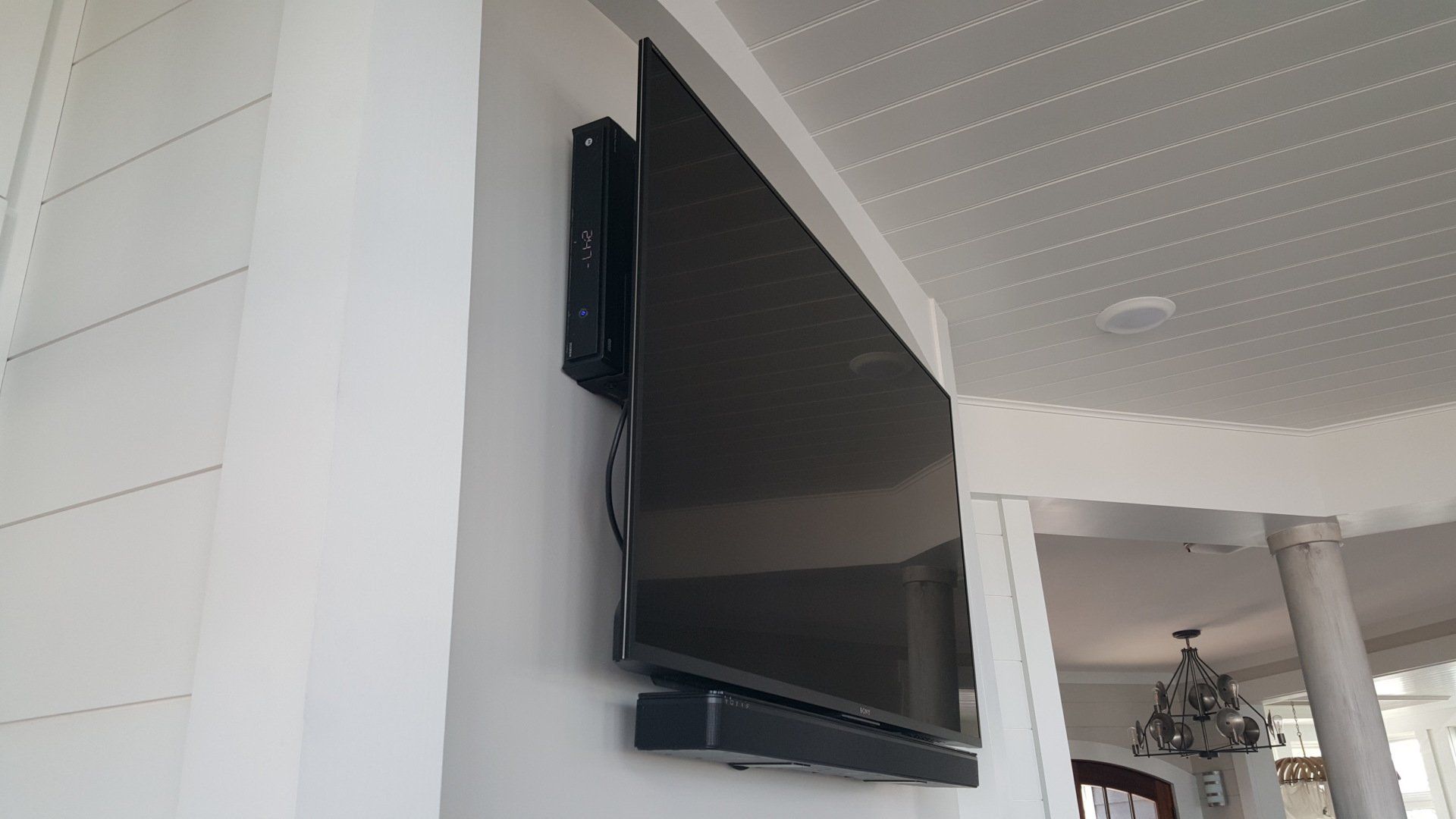 a flat screen tv mounted on a white wall with a cable box mounted behind the TV in northern ohio