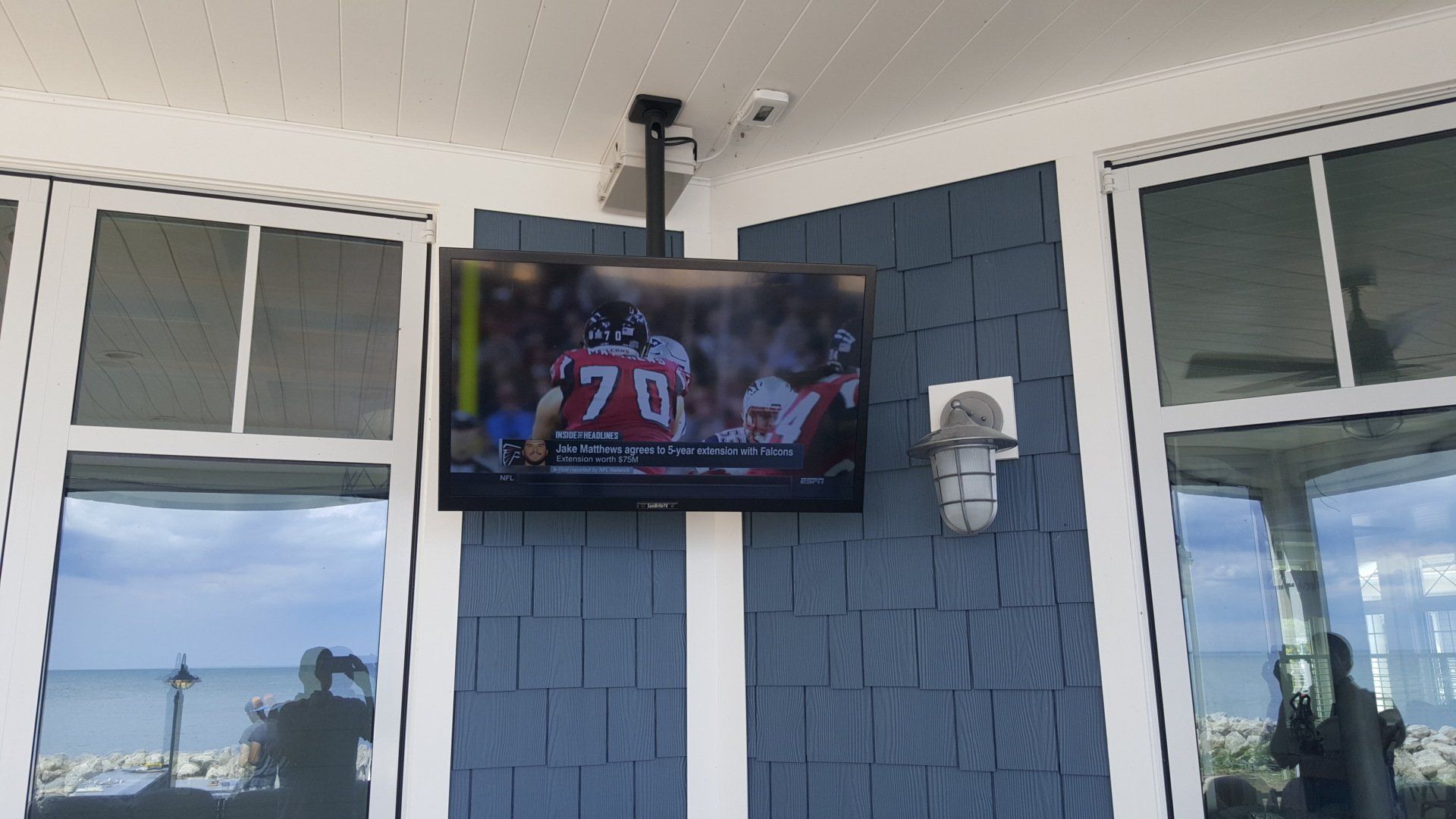 an outdoor television shows a football game with an outdoor soundbar also