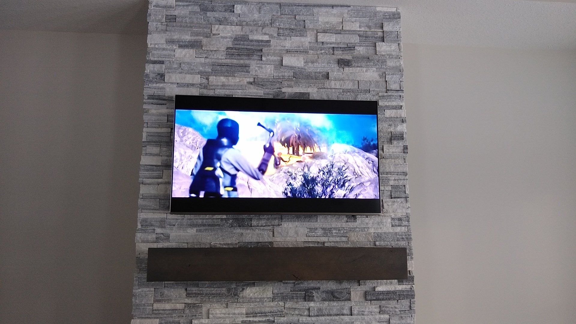 a flat screen TV is mounted to a stone wall above a fireplace mantle in north central ohio
