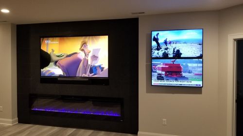 A living room with a fireplace and two flat screen tvs mounted in north central ohio