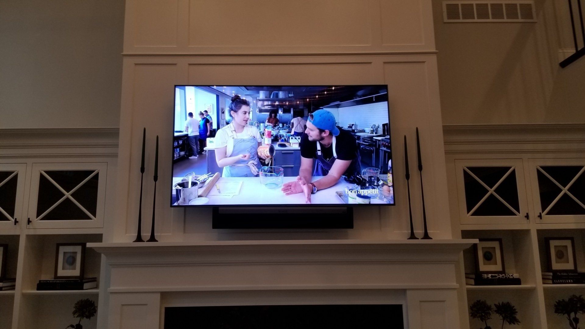 a flat screen tv shows a man and woman cooking in a kitchen and a sonos soundbar installed by fisher electronics in northern ohio.