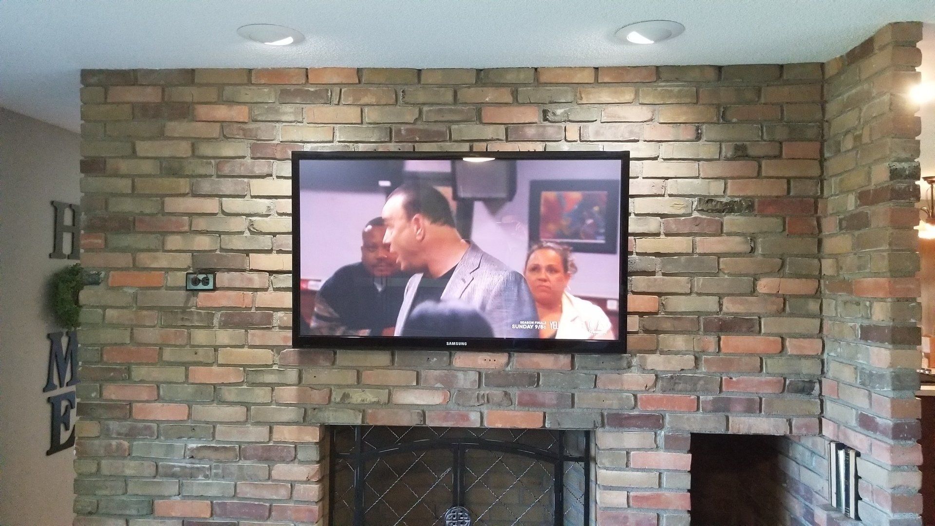 a samsung television is mounted on a brick wall above a fireplace in sandusky ohio