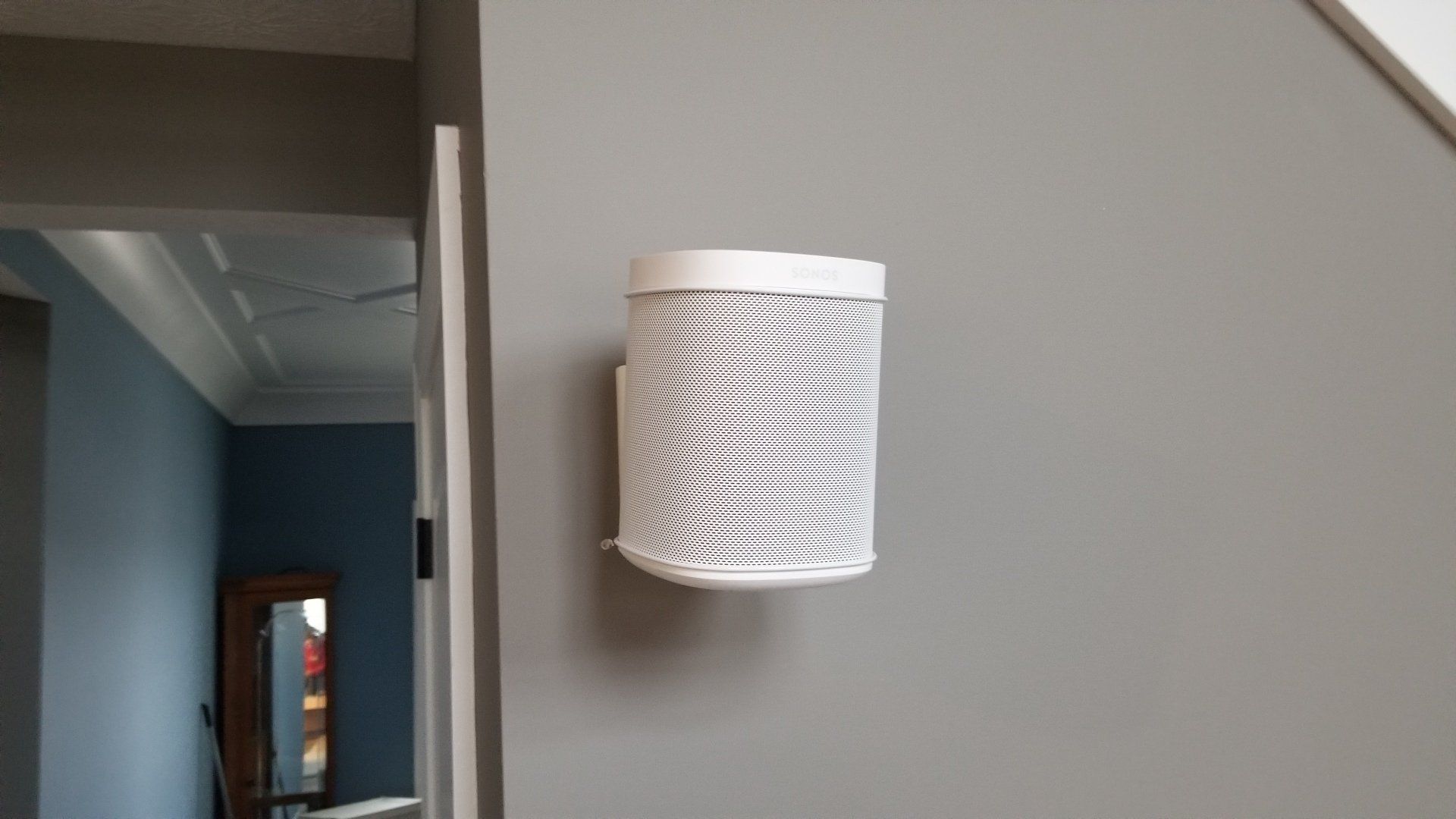a white sonos rear speaker mounted on a gray wall installed by fisher electronics in northern ohio.