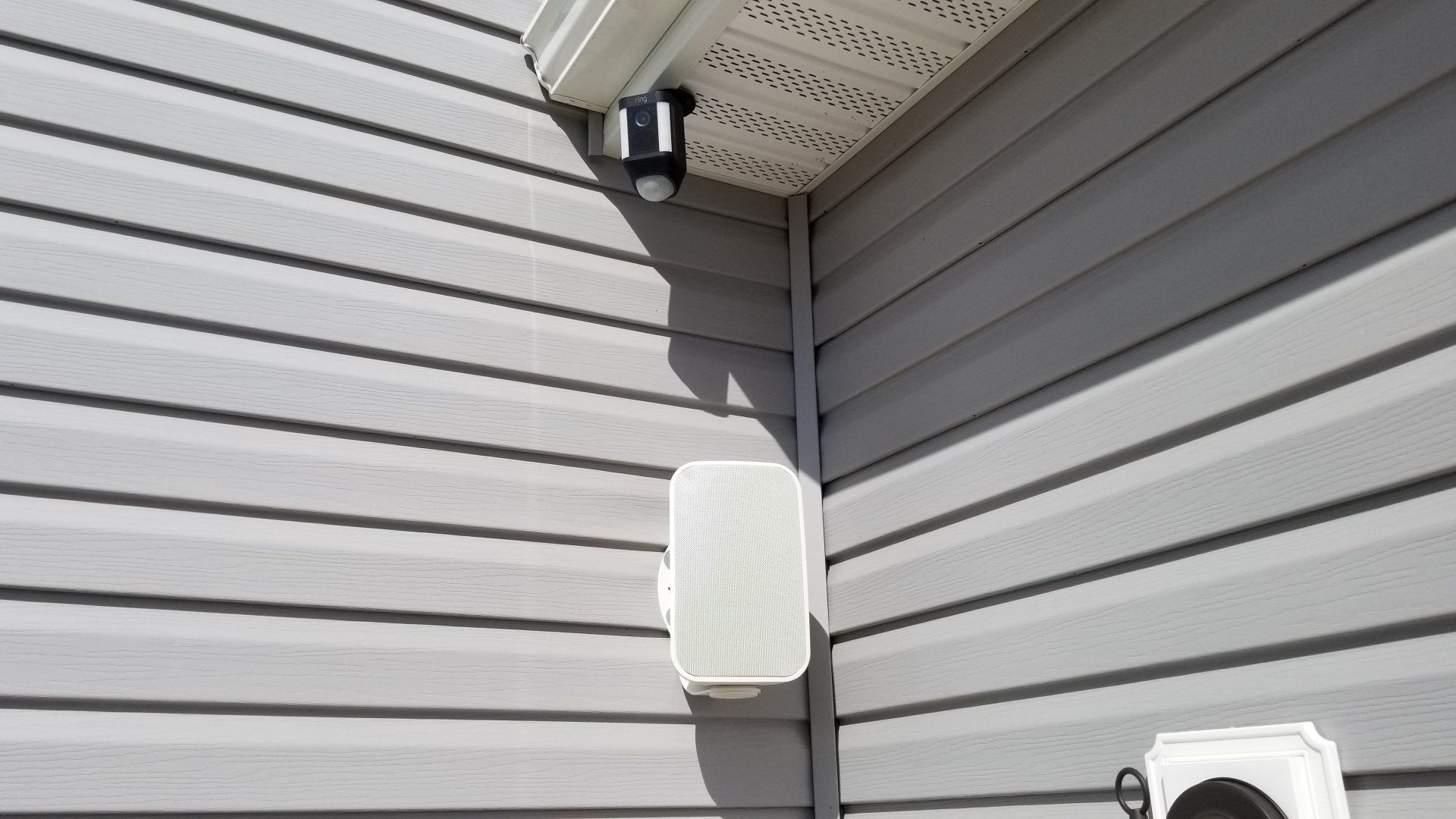 a white outdoor speaker on the side of a house for outdoor audio