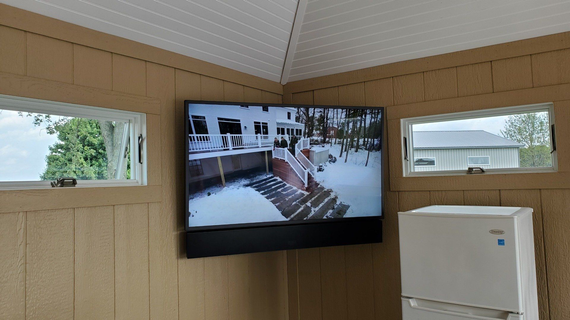 a samsung terrace outdoor television is mounted in a pool house with a outdoor soundbar below it
