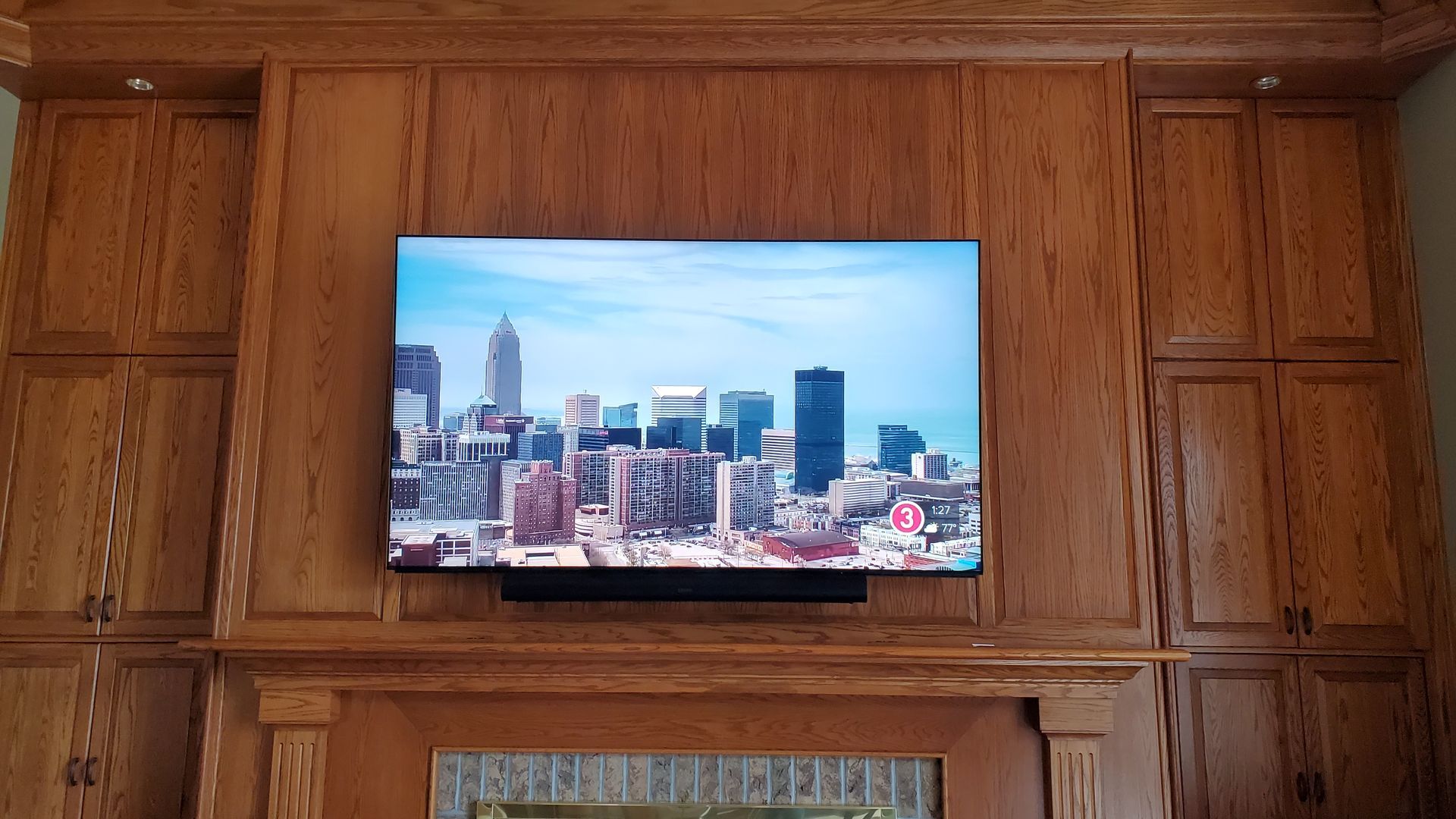 a flat screen tv and soundbar is mounted above a fireplace with installation by fisher electronics in northern ohio