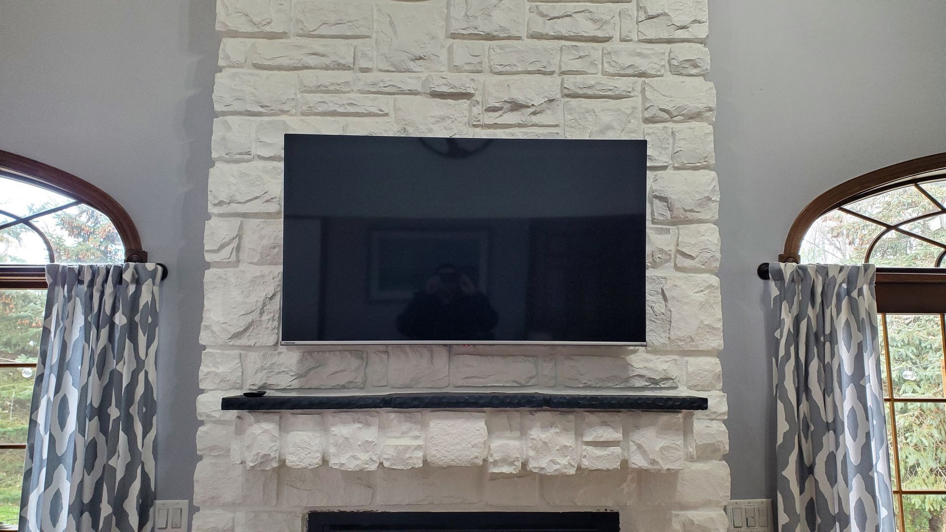 a flat screen tv mounted on a stone fireplace in north central ohio