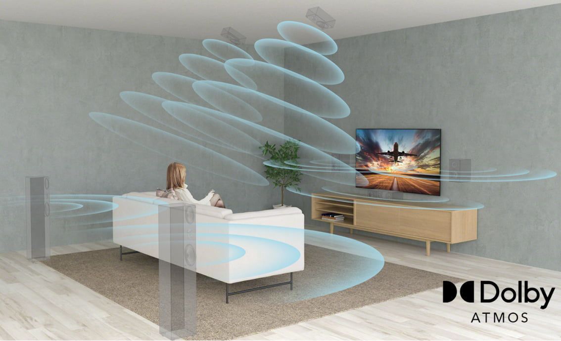 a woman sits on a couch in front of a sony tv that provides dolby atmos sound