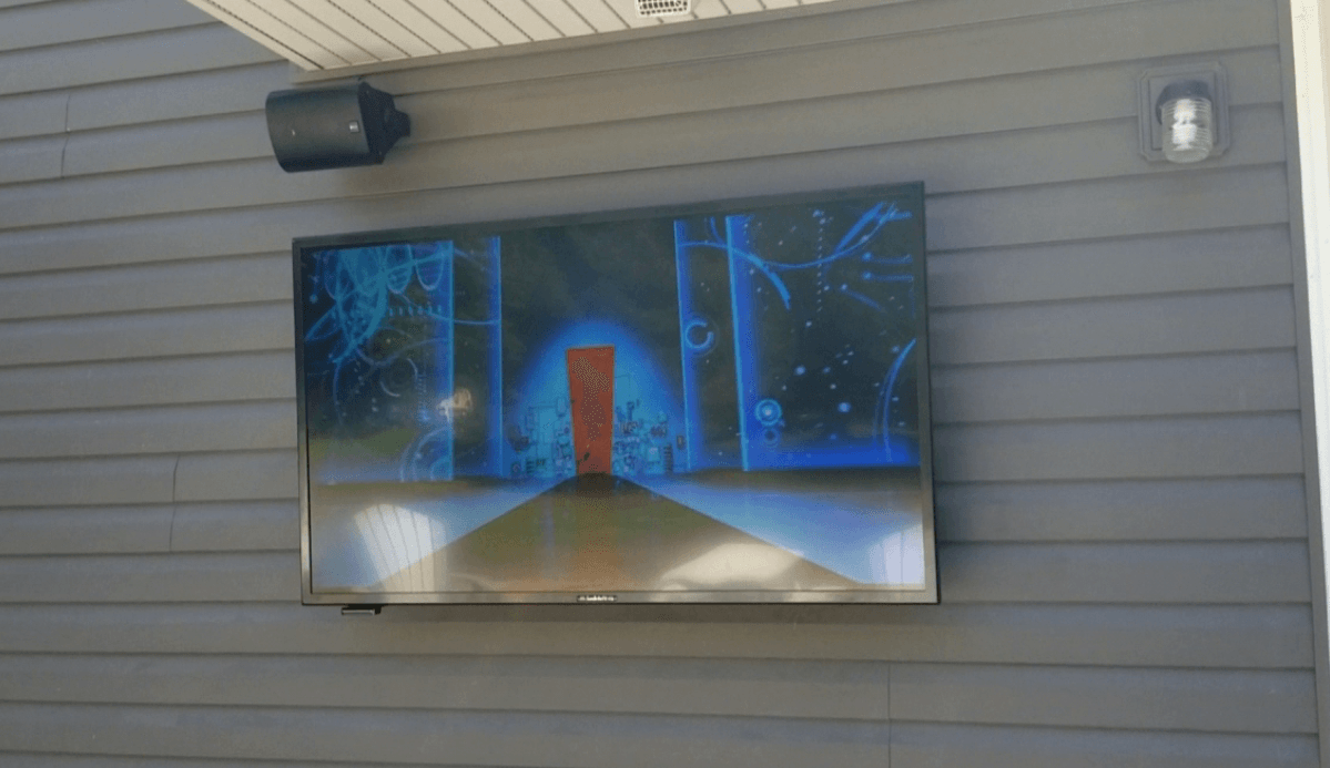 a samsung outdoor tv is mounted on the side of a house with outdoor speakers
